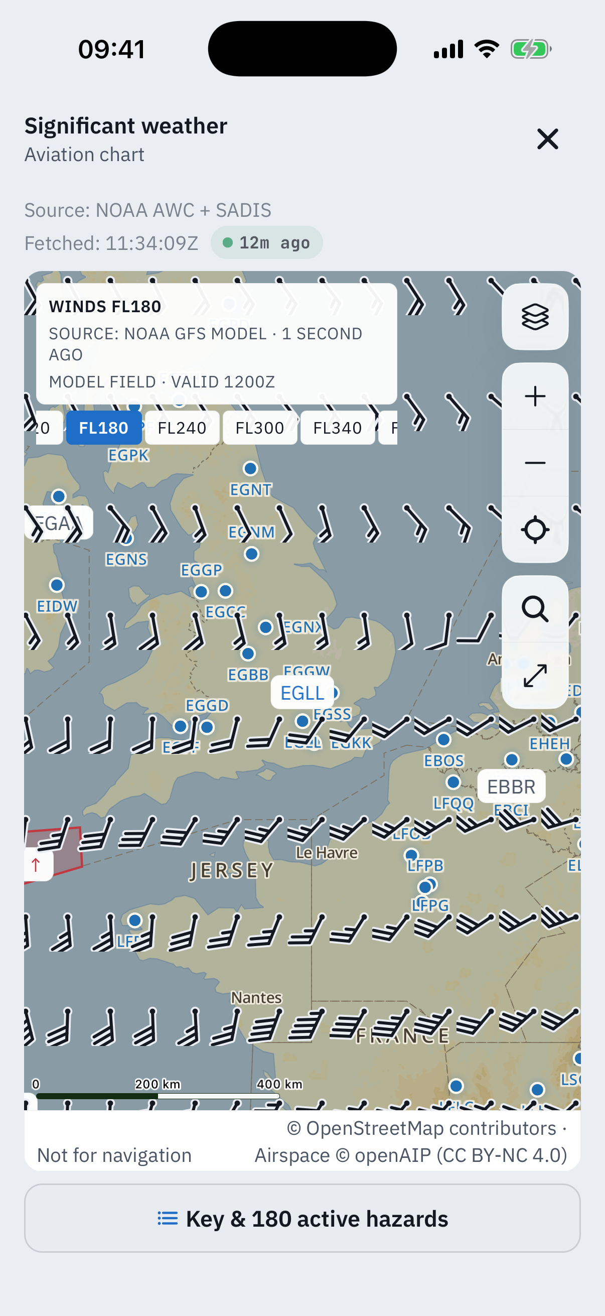 The significant weather chart covered in wind barbs at flight level 180: the header reads Winds FL180, Source NOAA GFS model, 1 second ago, model field valid 1200Z, with level chips for FL180, FL240, FL300 and FL340, the barbs flowing across the UK and France between the airport dots
