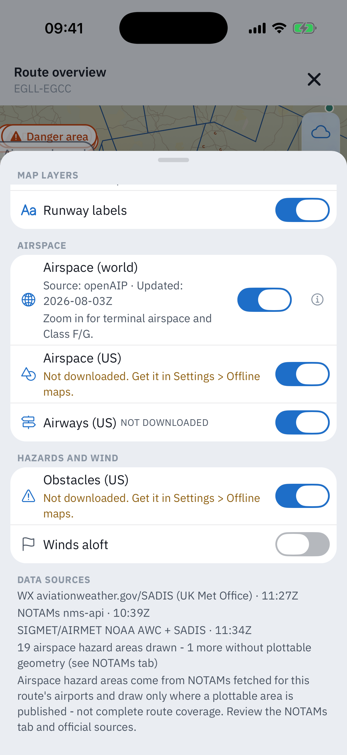 The Map layers sheet scrolled to its foot: the Airspace world row with its openAIP credit, Airspace US and Airways US rows with Not downloaded lines, Obstacles US and a Winds aloft toggle switched off, then the Data sources block reading WX aviationweather.gov slash SADIS UK Met Office 11:27Z, NOTAMs nms-api 10:39Z, SIGMET AIRMET NOAA AWC plus SADIS 11:34Z, 19 airspace hazard areas drawn, 1 more without plottable geometry, and the caveat that hazard areas draw only where a plottable area is published